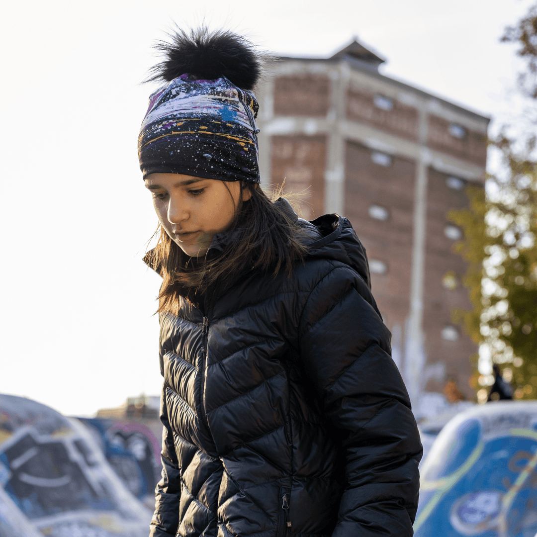 Young girl in a black puffer jacket and the Abracadabra beanie with a fluffy pompom