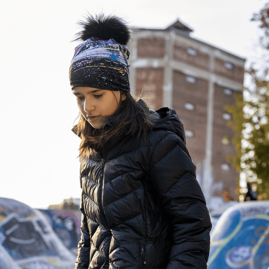 Young girl in a black puffer jacket and the Abracadabra beanie with a fluffy pompom