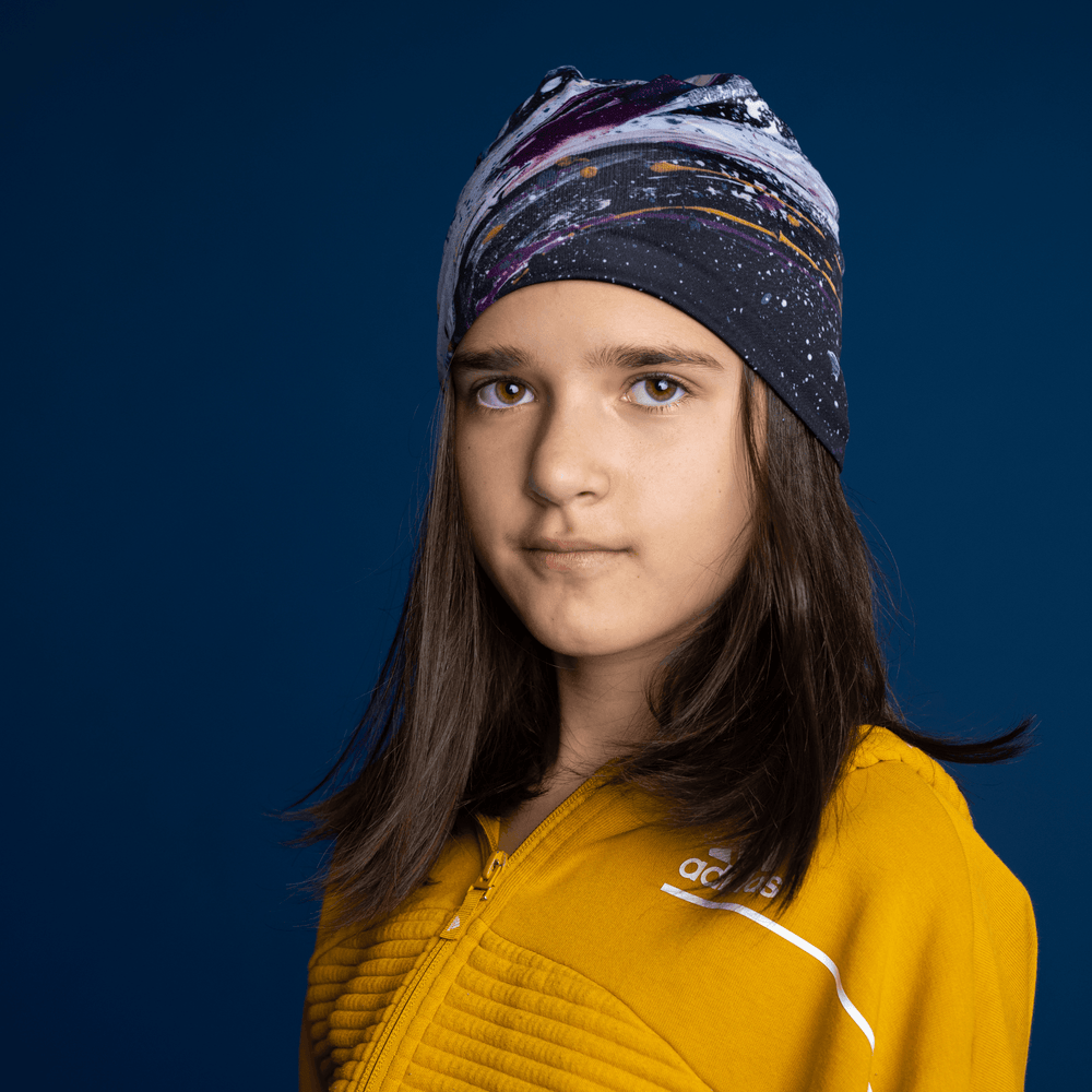 Young girl wearing the Abracadabra Beanie as a headband, displaying the abstract art pattern.