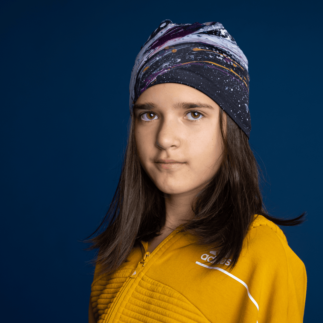 Young girl wearing the Abracadabra Beanie as a headband, displaying the abstract art pattern.
