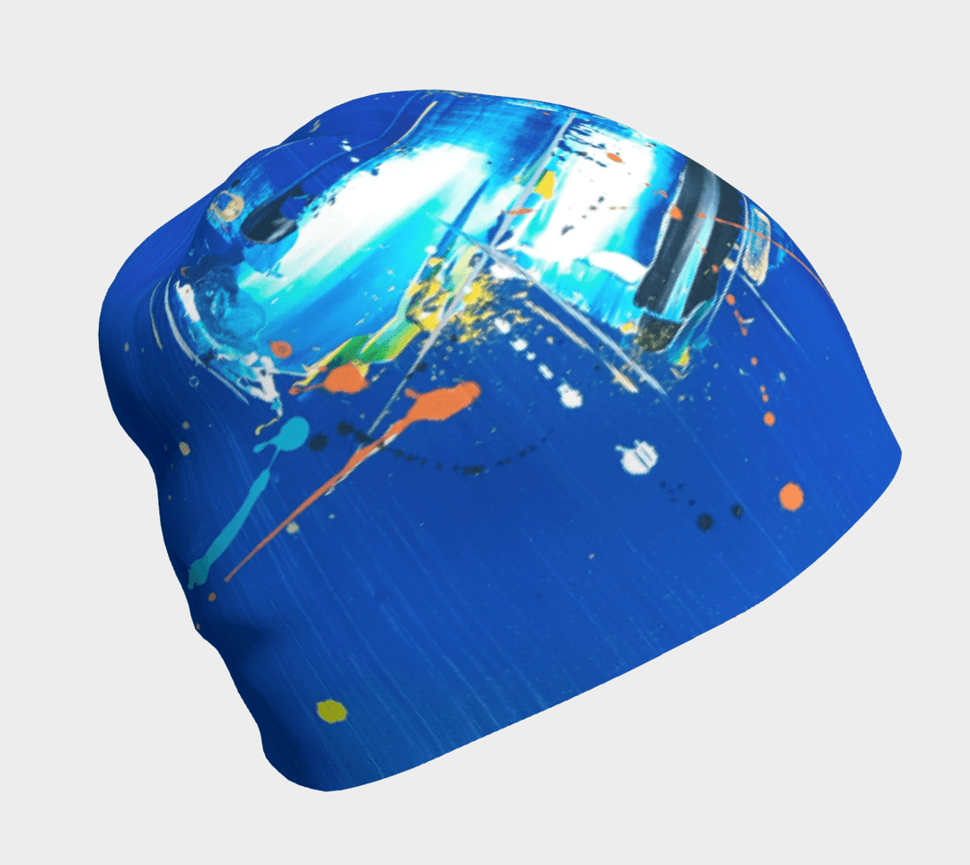Blue beanie with a dynamic abstract art pattern featuring white, yellow, and orange splashes on a vibrant blue background.