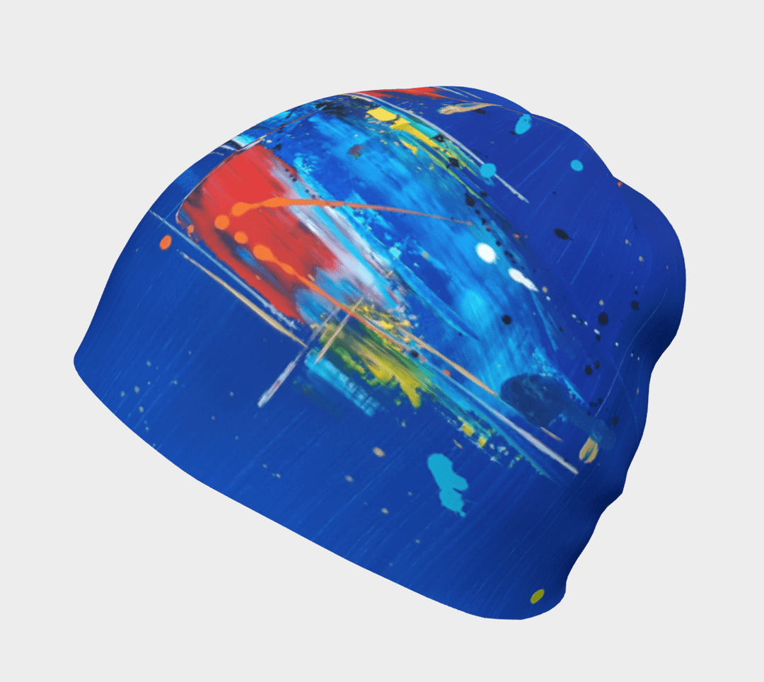 Close-up of a blue beanie showcasing a bold abstract design with energetic brushstrokes in red, white, and blue.