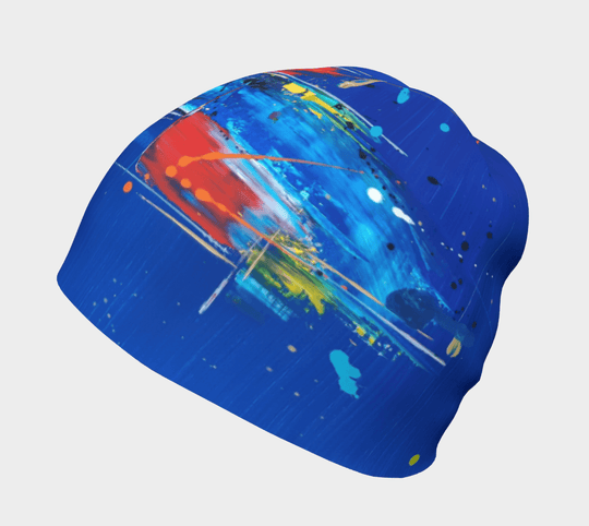 Close-up of a blue beanie showcasing a bold abstract design with energetic brushstrokes in red, white, and blue.
