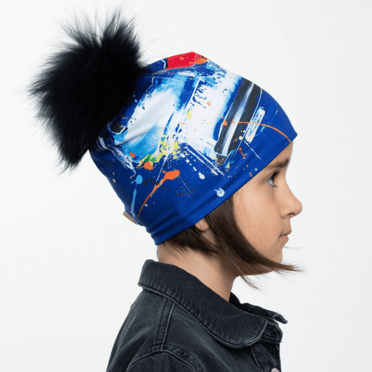 Side profile of a young girl wearing the Abstract Blue Beanie with a removable black pompom.