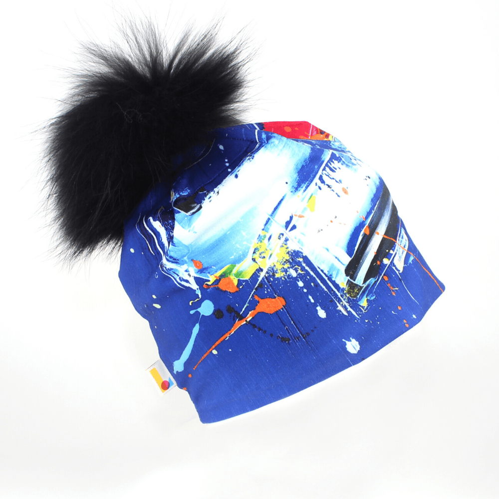 Abstract Blue Beanie with a large black fluffy pompom against a white background.