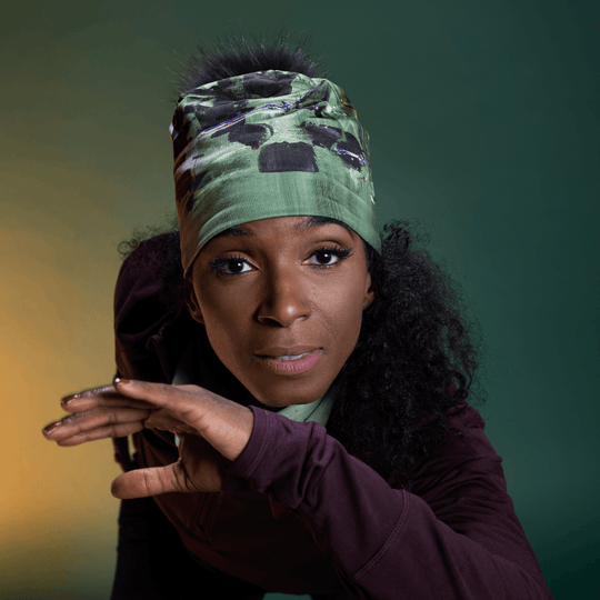 Woman wearing the Amazonia Beanie as a headband, showcasing the green abstract art pattern.