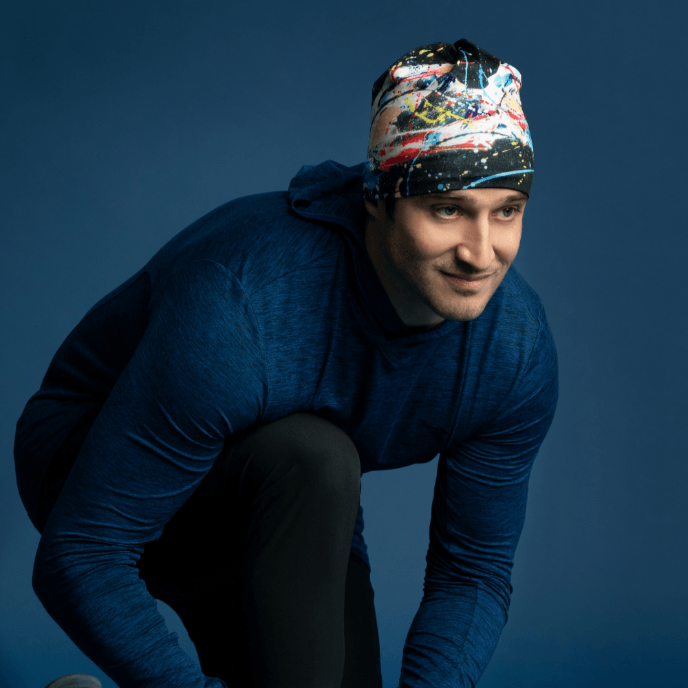 Man wearing the Black Horse Beanie, crouching down as if tying a shoe during a run.