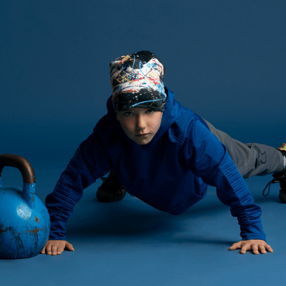 Young boy wearing the Black Horse Beanie, performing a push-up next to a kettlebell.