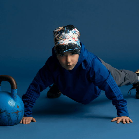 Young boy wearing the Black Horse Beanie, performing a push-up next to a kettlebell.