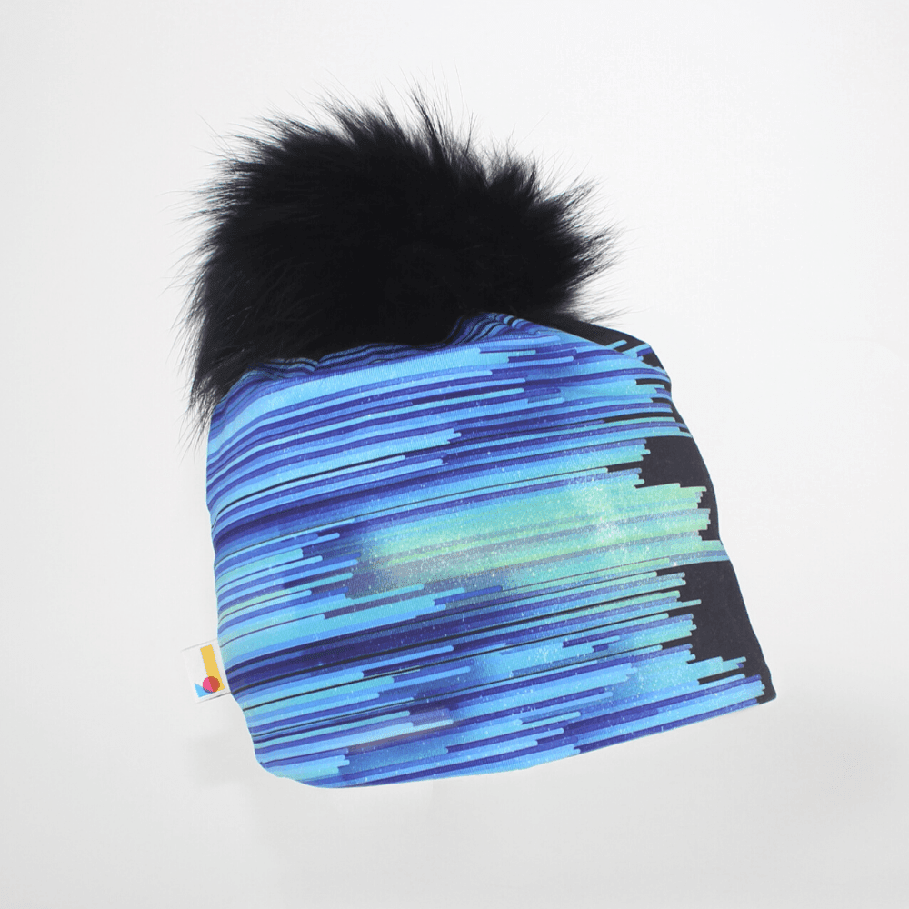 Black War Beanie with blue and purple abstract stripes and a large black pompom against a white background.