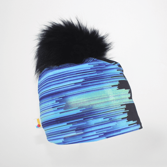 Black War Beanie with blue and purple abstract stripes and a large black pompom against a white background.
