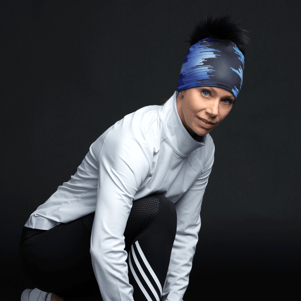 Woman wearing the Black War Beanie with a black pompom and abstract blue pattern, posed in athletic wear.