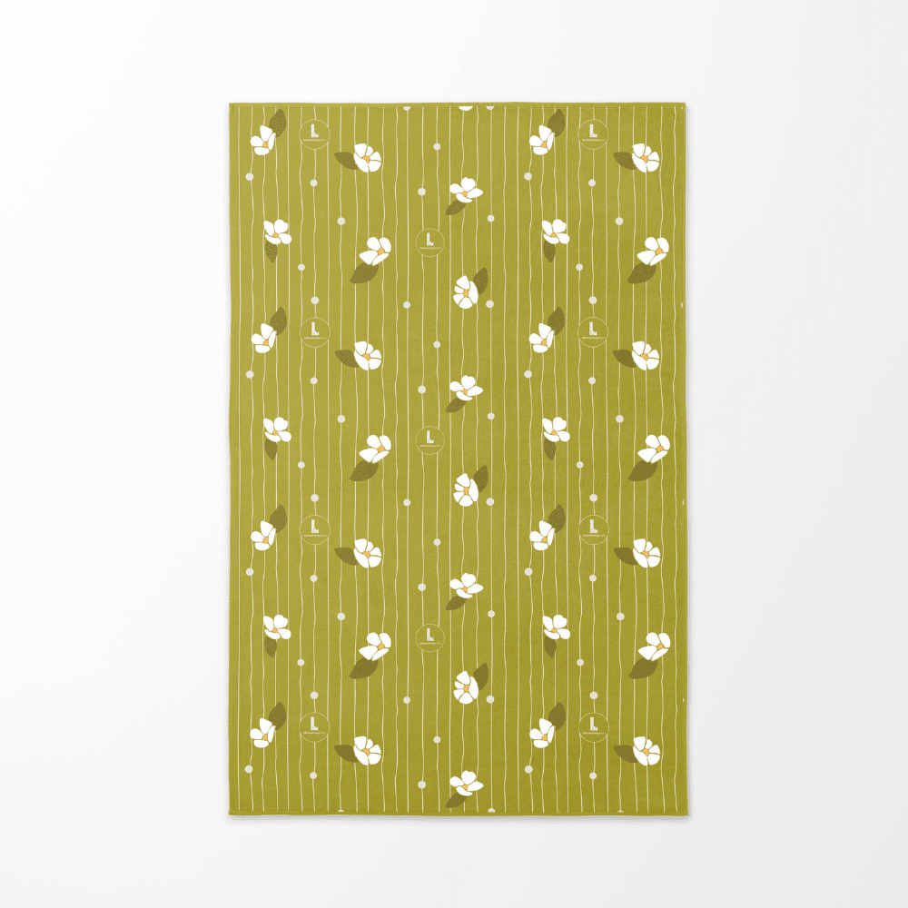 The reverse side of the Chrysalide artistic beach towel, featuring a soft green background with white floral motifs and vertical lines.