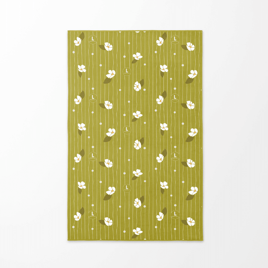 The reverse side of the Chrysalide artistic beach towel, featuring a soft green background with white floral motifs and vertical lines.