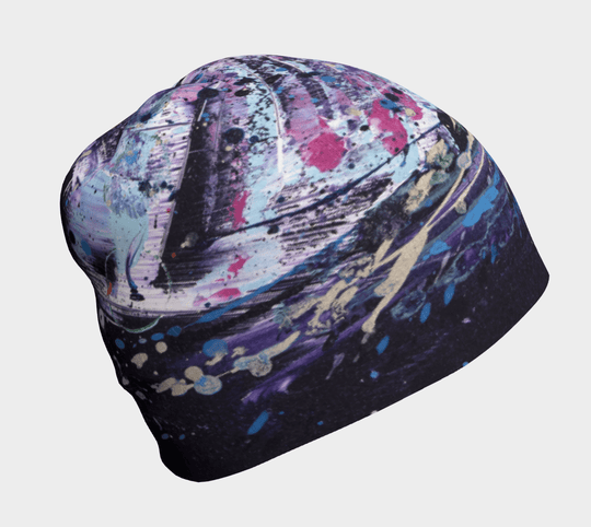 Close-up of a beanie with a vibrant, abstract splash-art design in purple, blue, and pink.