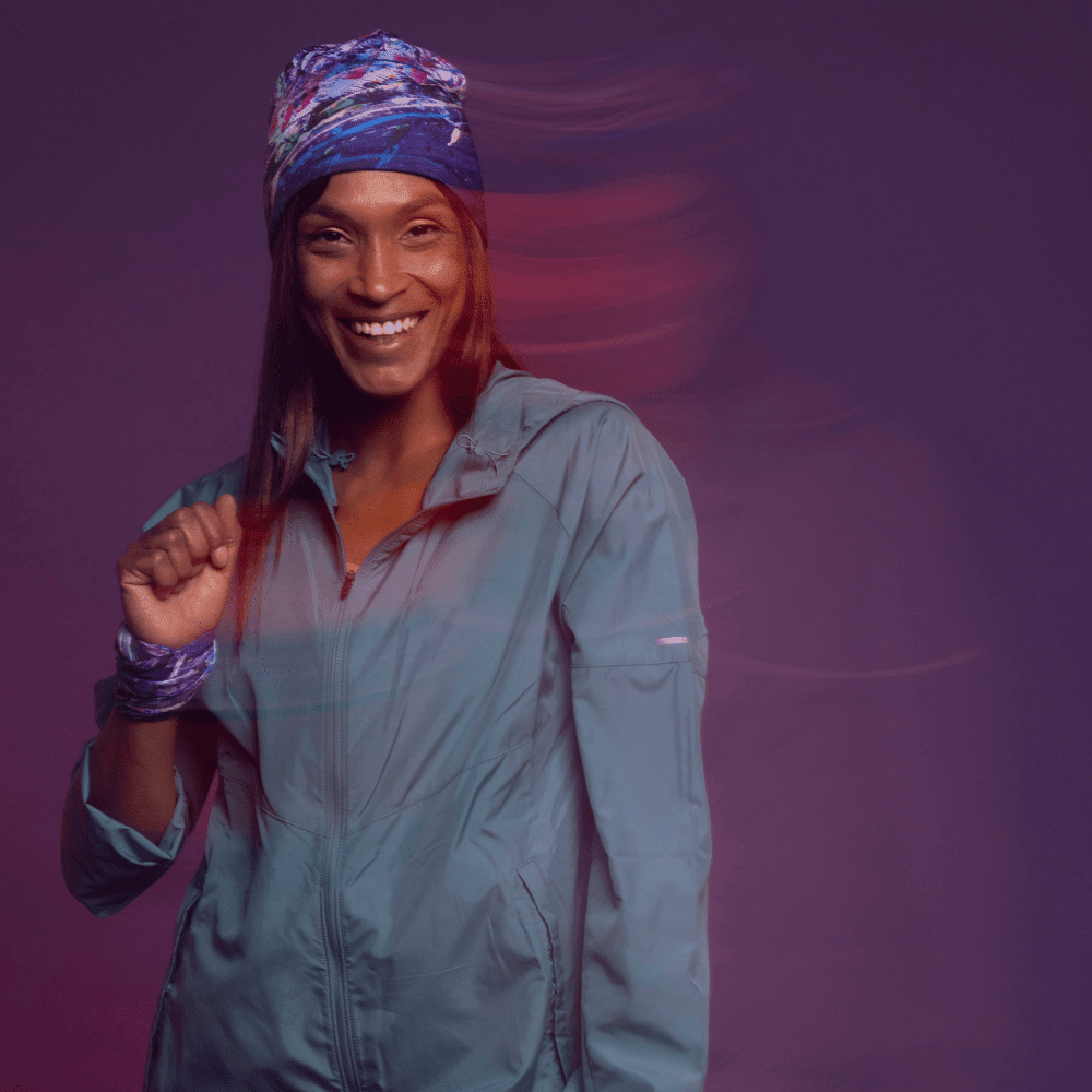 A smiling woman wearing a blue jacket and a headband with the Cosmic art pattern.