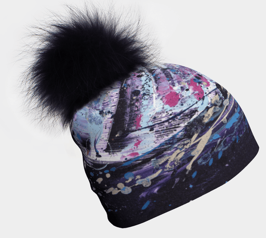 Cosmic Beanie With Pompom featuring abstract art and a fluffy black pompom on a white background.
