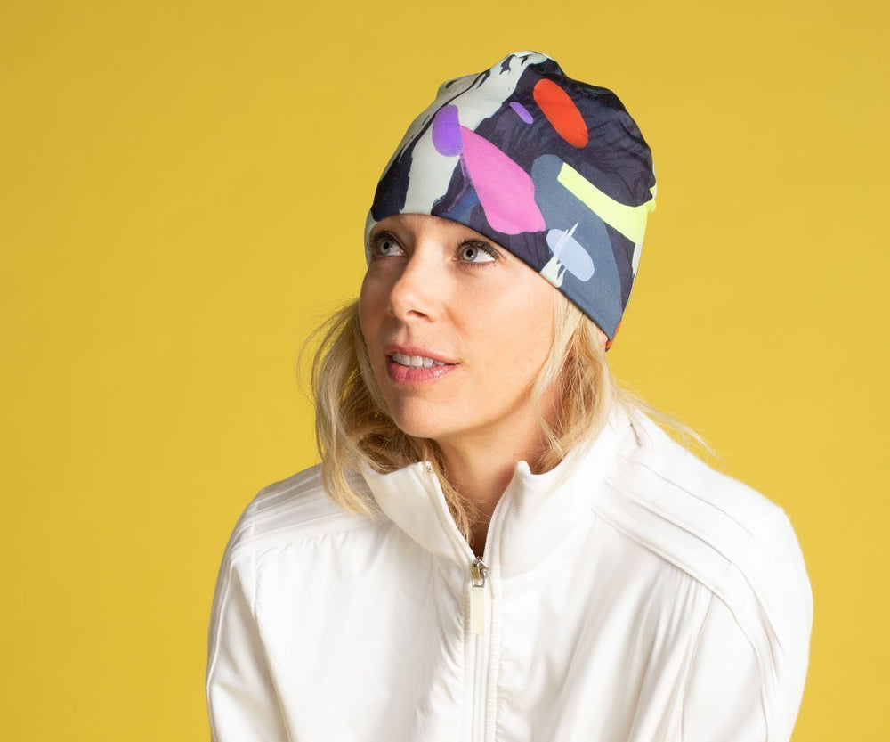Woman wearing the abstract crow graphic beanie hat with a white jacket