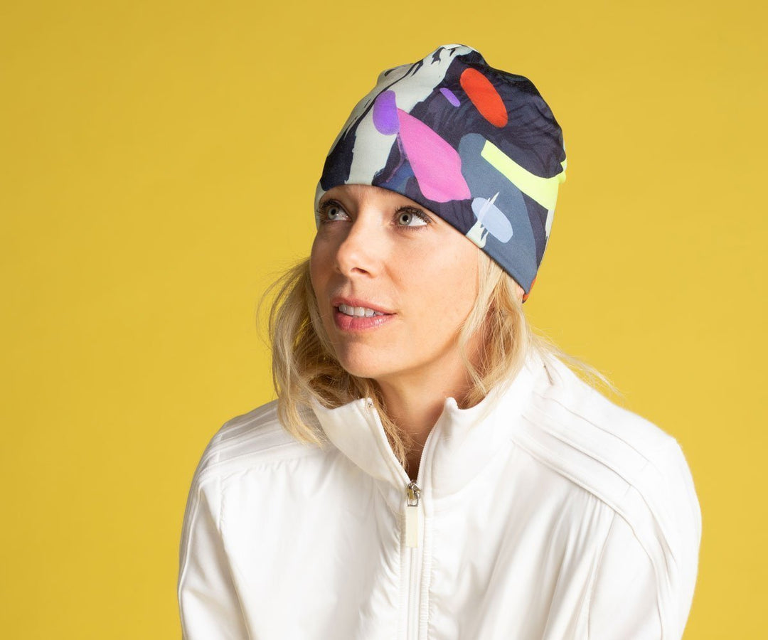 Woman wearing the abstract crow graphic beanie hat with a white jacket