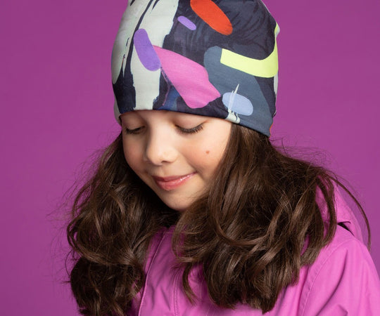 Young girl wearing the abstract crow graphic beanie hat with a pink jacket