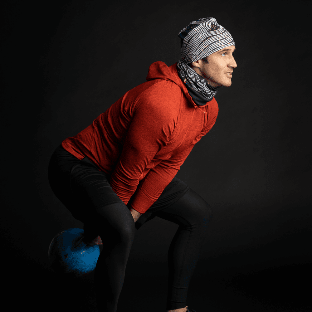 A man wearing a Dark Steel beanie and neck gaiter during a kettlebell workout.