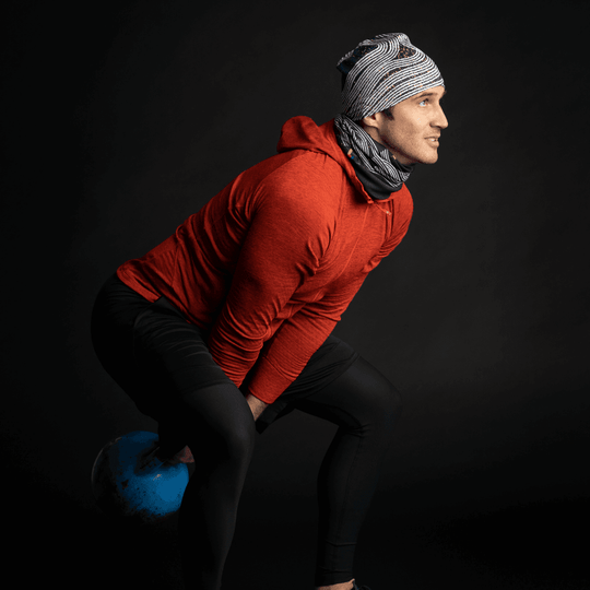 A man wearing a Dark Steel beanie and neck gaiter during a kettlebell workout.