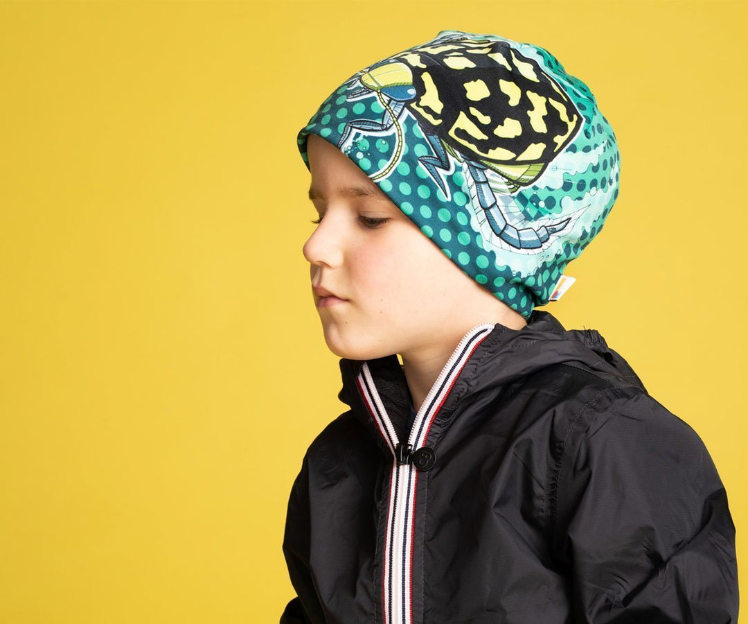 A child wearing the Diving Beetle Beanie with a black jacket, looking thoughtfully to the side.