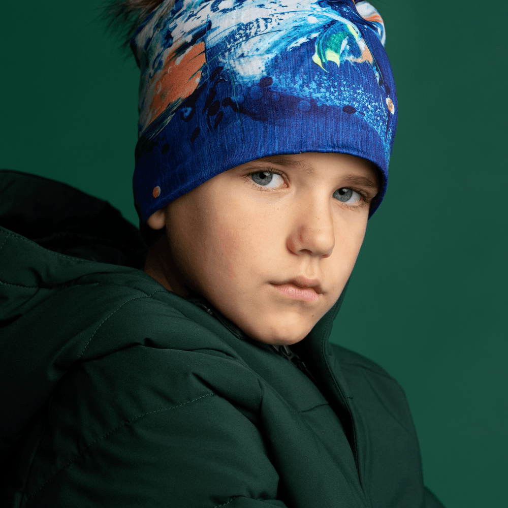 Close-up of a young boy wearing the blue abstract art beanie, looking forward.
