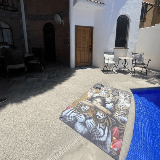 The Felines XL artistic towel draped by a pool, featuring the vibrant wildlife illustration.