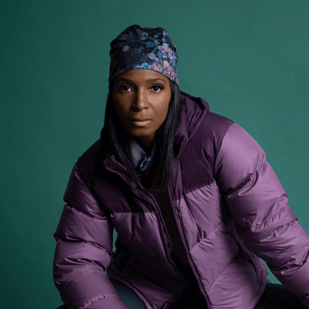 Woman wearing a purple puffer jacket and a beanie with a dark floral print.