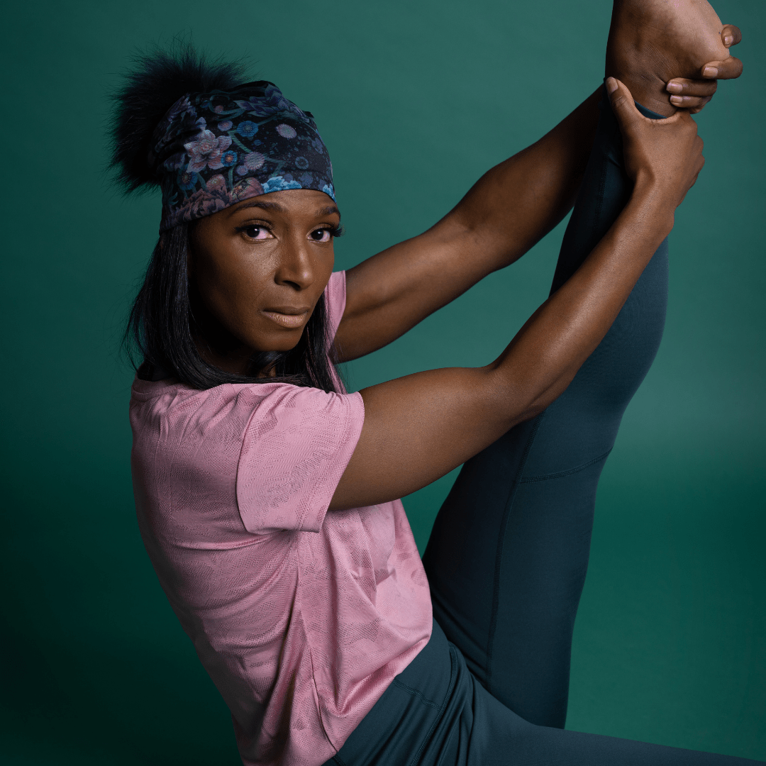 Close-up of a woman performing a difficult yoga pose, wearing the Flora Pompom Beanie.