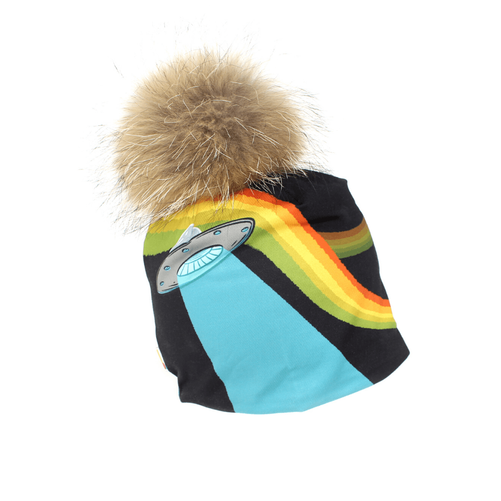 Black beanie with a colourful rainbow stripe and a flying saucer appliqué, topped with a large, fluffy brown fur pompom.