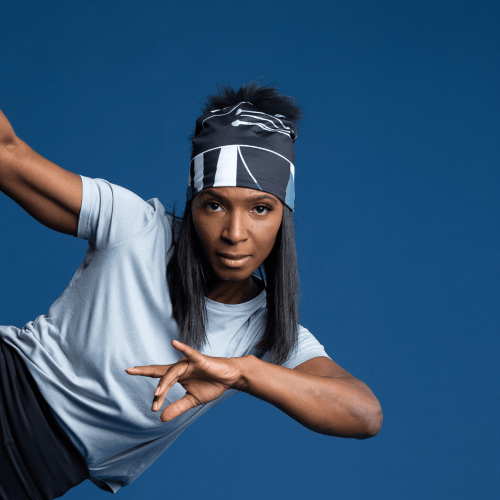 Woman wearing the black and grey geometric print beanie as a headband during a dance pose.