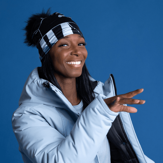 Woman wearing the black and grey geometric print beanie and a light blue winter coat, smiling.