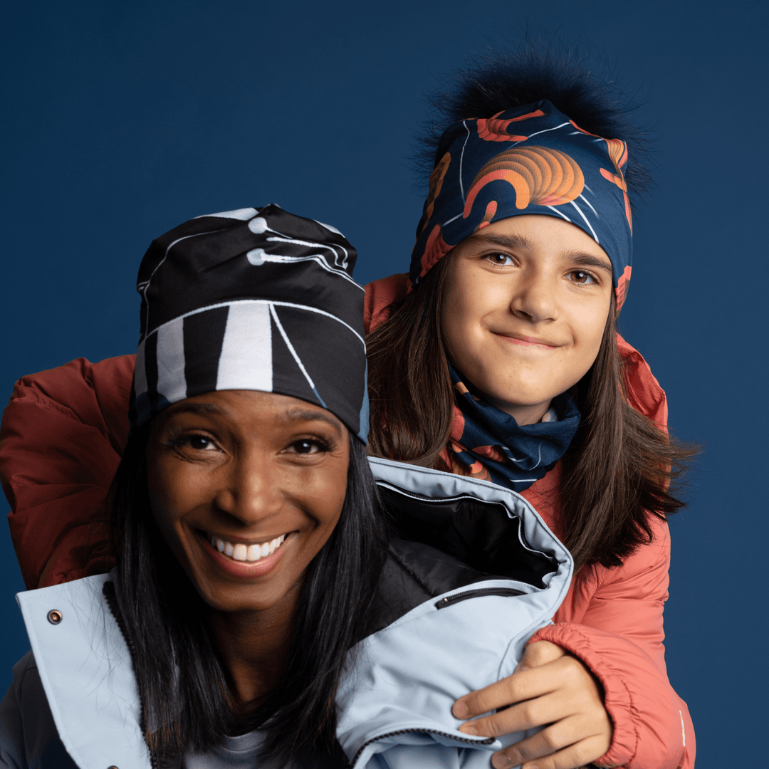 A woman and a child wearing colourful winter jackets and beanies, smiling at the camera.