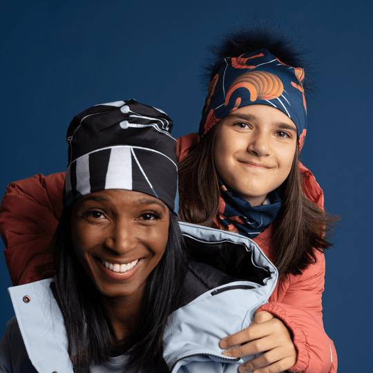 A woman and a child wearing colourful winter jackets and beanies, smiling at the camera.