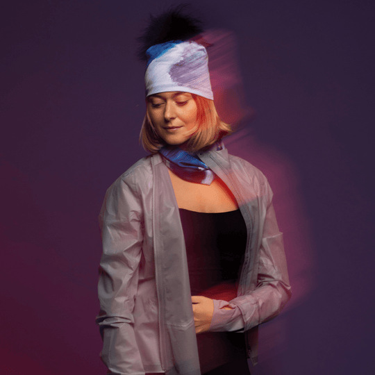Woman wearing a blue and white abstract Golden Sea Beanie and a matching neck tube, with a blurred motion effect.