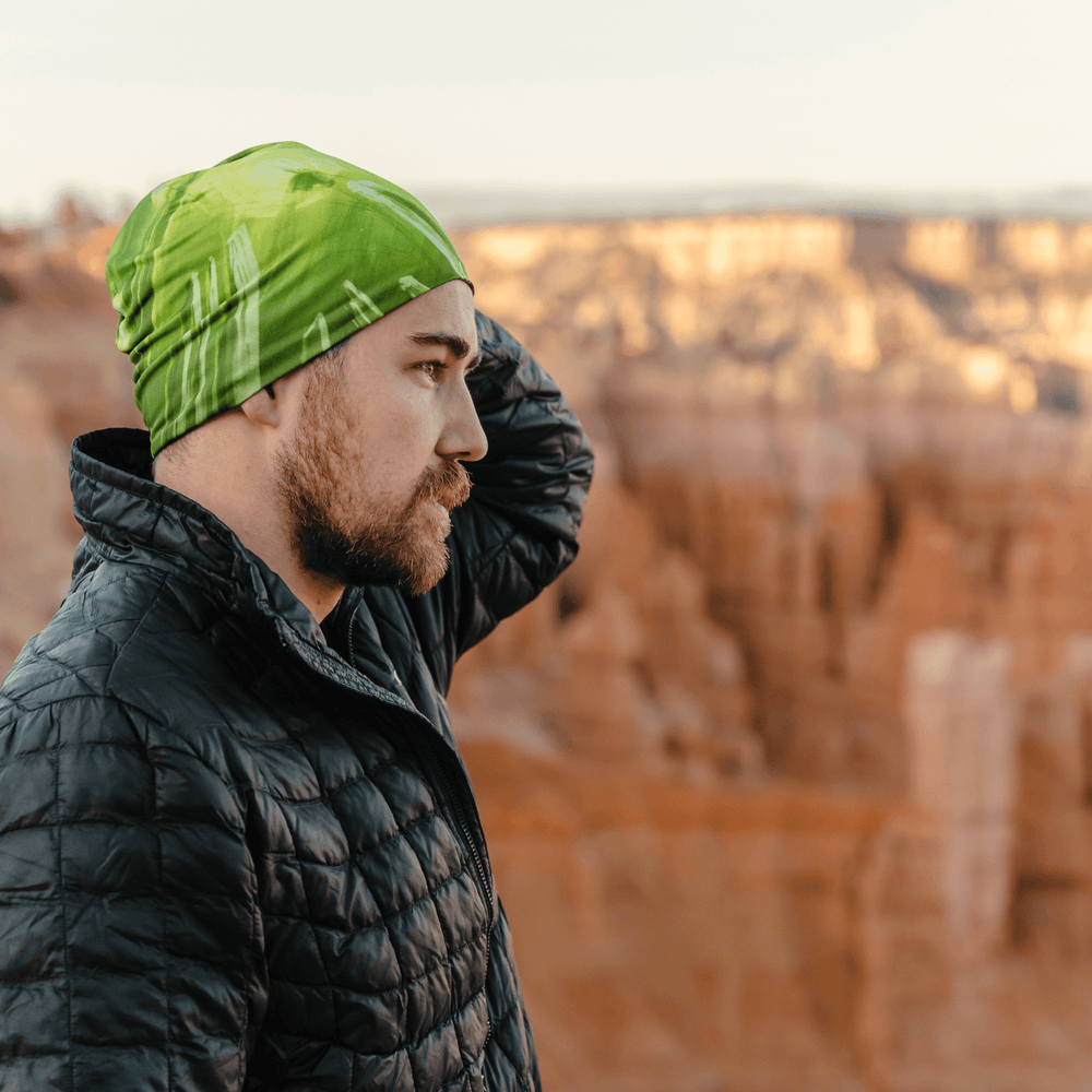 Man wearing the Green Light Sports Beanie outdoors, with a rocky canyon landscape behind him.