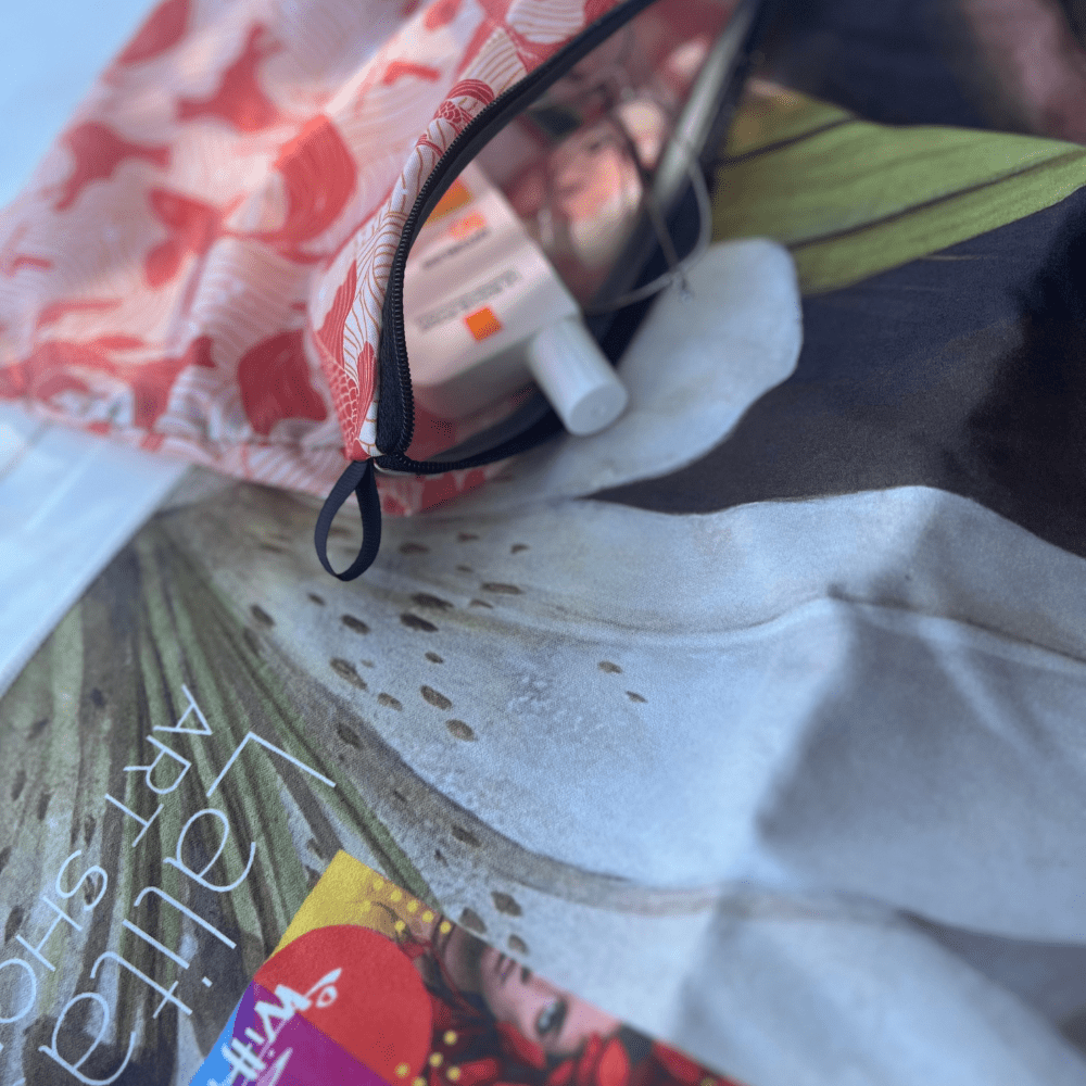 Close-up of the Guerrière Pacifique towel and its included pouch, showing sunscreen and toiletries.