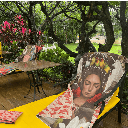The Guerrière Pacifique towel draped over yellow lounge chairs and a table in an outdoor garden setting.