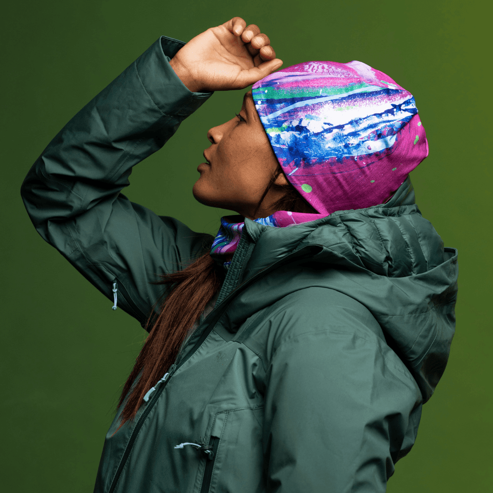 Woman wearing the Hope Beanie and neck tube, shielding her eyes in a winter jacket.