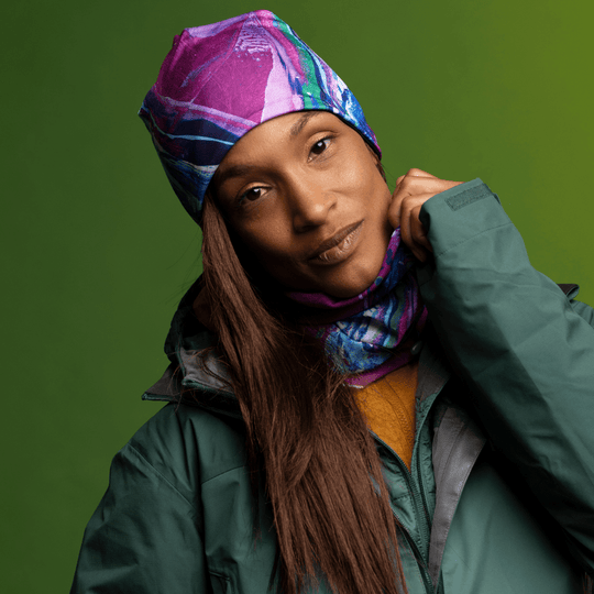 Woman models the Hope Beanie and coordinating neck gaiter, adjusting the scarf portion.