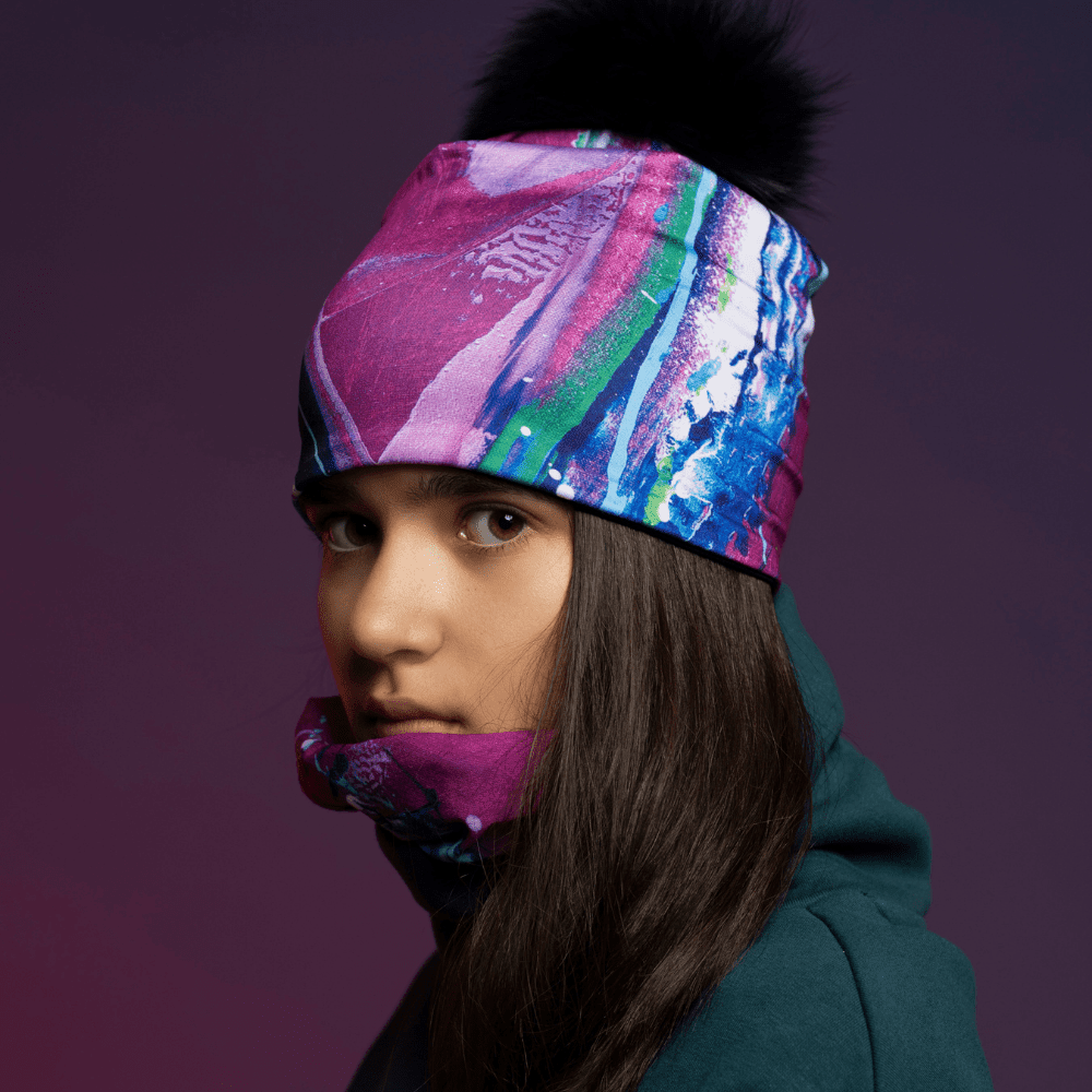 A young person wearing the Hope tube as a beanie and around their neck, with a purple background.