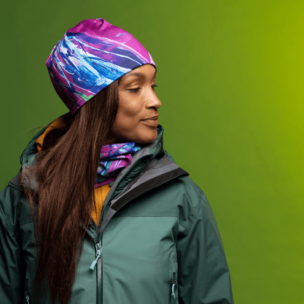 Woman wearing a green jacket, a yellow sweater, and the Hope tube as a beanie and neck gaiter.