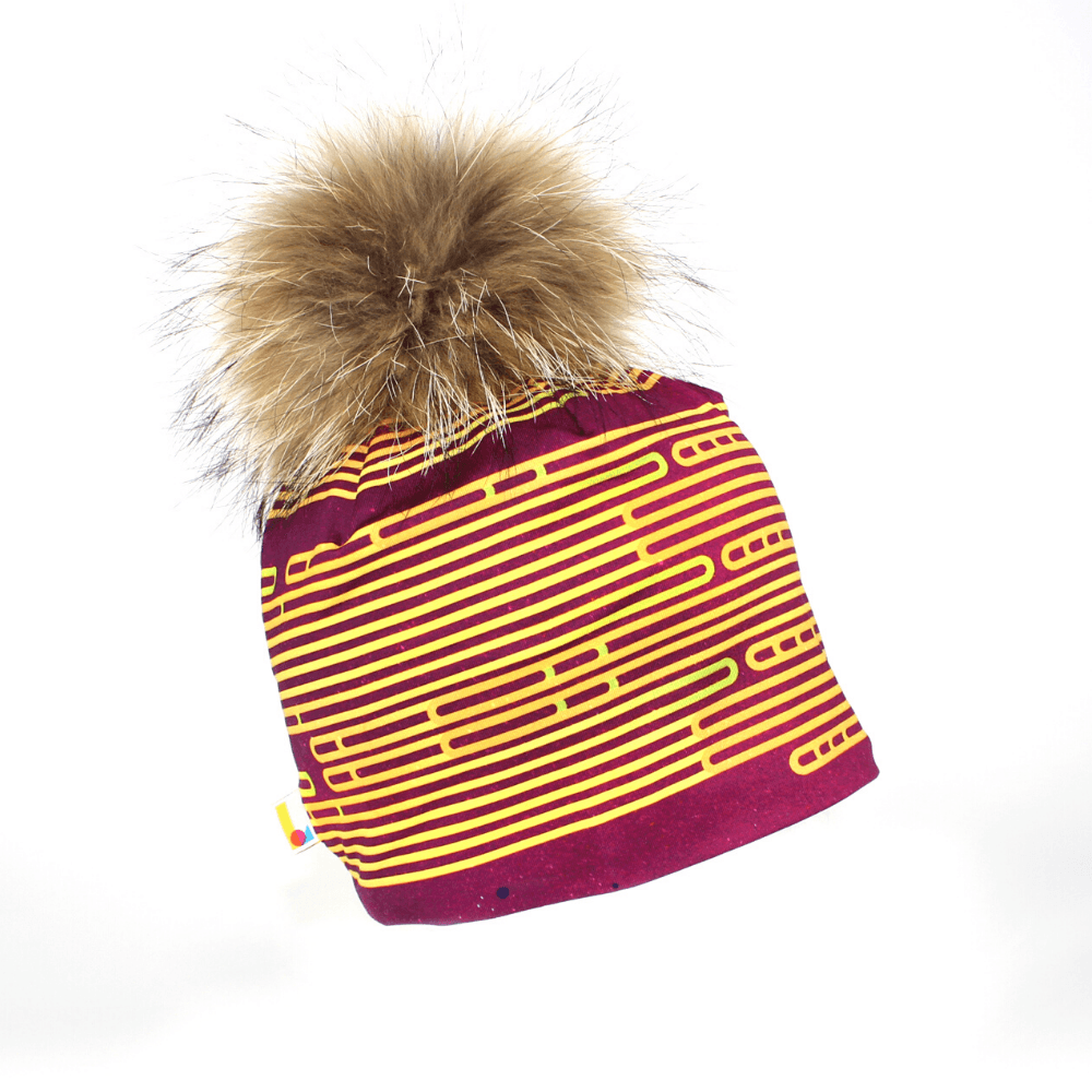 Magenta and yellow striped beanie with a large fluffy brown pompom against a white background.