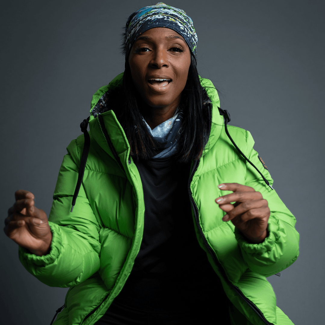 Woman wearing the Meduse Beanie as a headband, smiling, in a green puffer jacket.