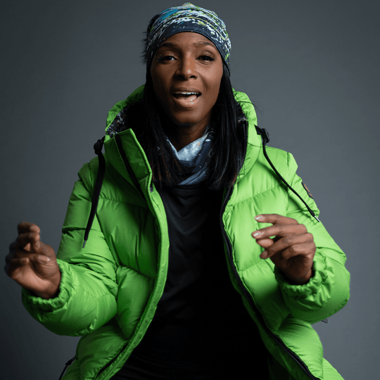 Woman wearing the Meduse Beanie as a headband, smiling, in a green puffer jacket.