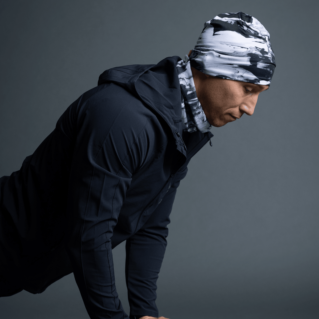 Man wearing a black and white abstract pattern beanie and matching neck gaiter, looking to the side.