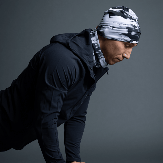 Man wearing a black and white abstract pattern beanie and matching neck gaiter, looking to the side.