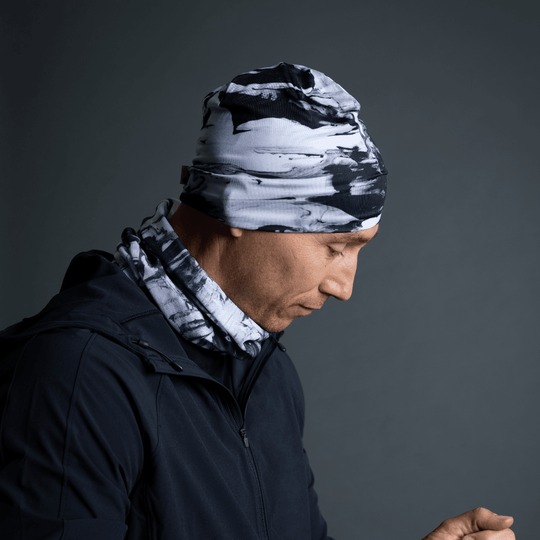 Man wearing a black and white abstract pattern beanie and matching neck gaiter, paired with a black jacket.